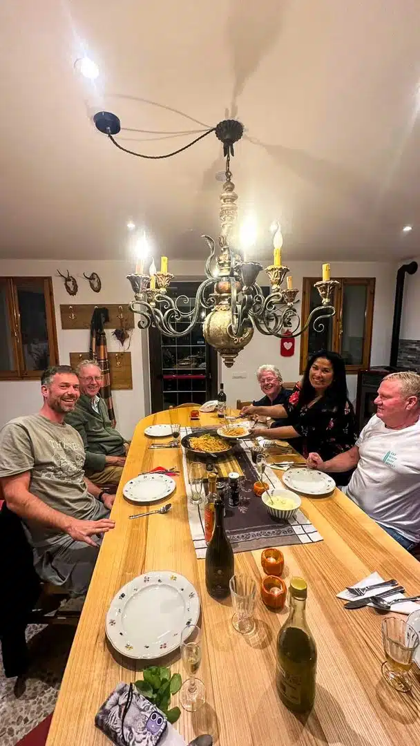Gruppe beim gemeinsamen Abendessen am Tisch unter einem Kronleuchter