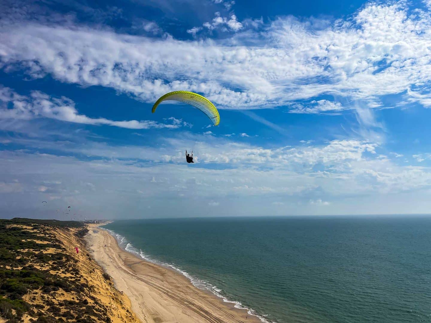 Gleitschirm über der Dünenküste von Matalascañas mit Strand und Meer, weitere Schirme in der Ferne