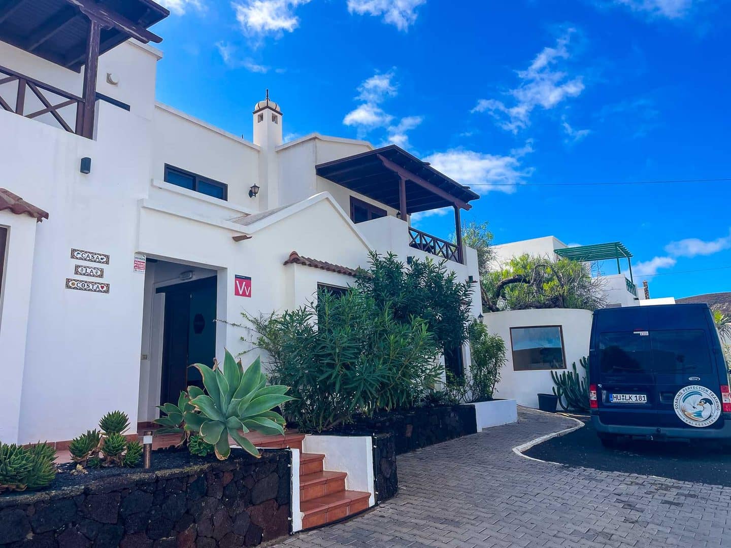 Weiße Casa La Costa auf Lanzarote mit Kakteen im Vorgarten und dem Papillon-Tourbus in der Einfahrt